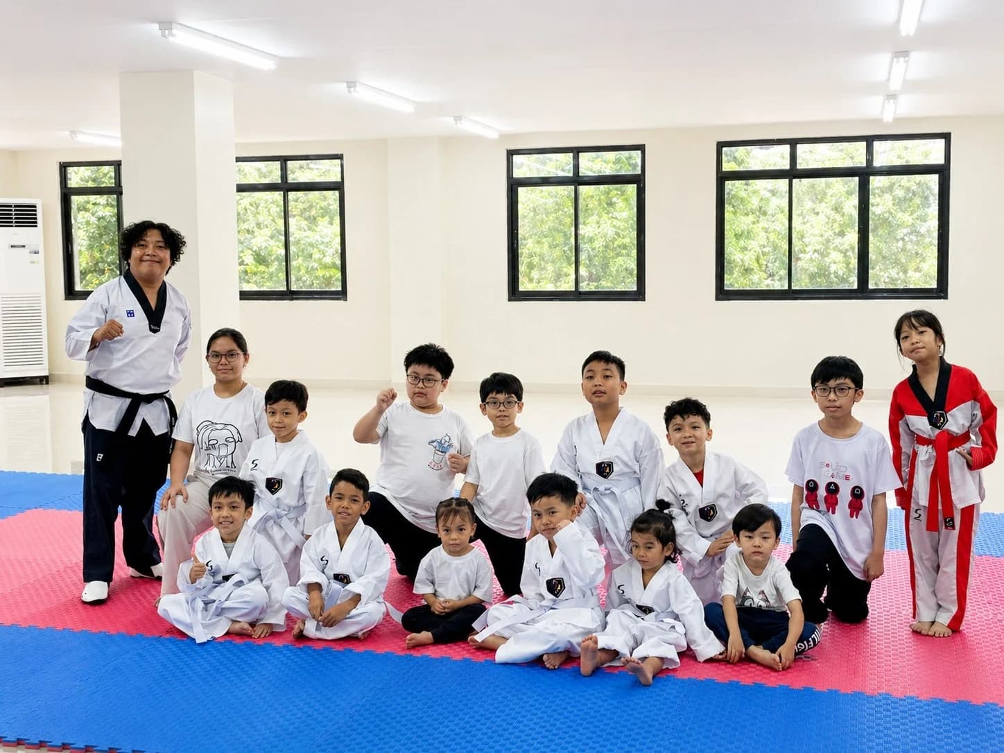 A black-belt coach with the Little Tigers class seated on the mat around him
