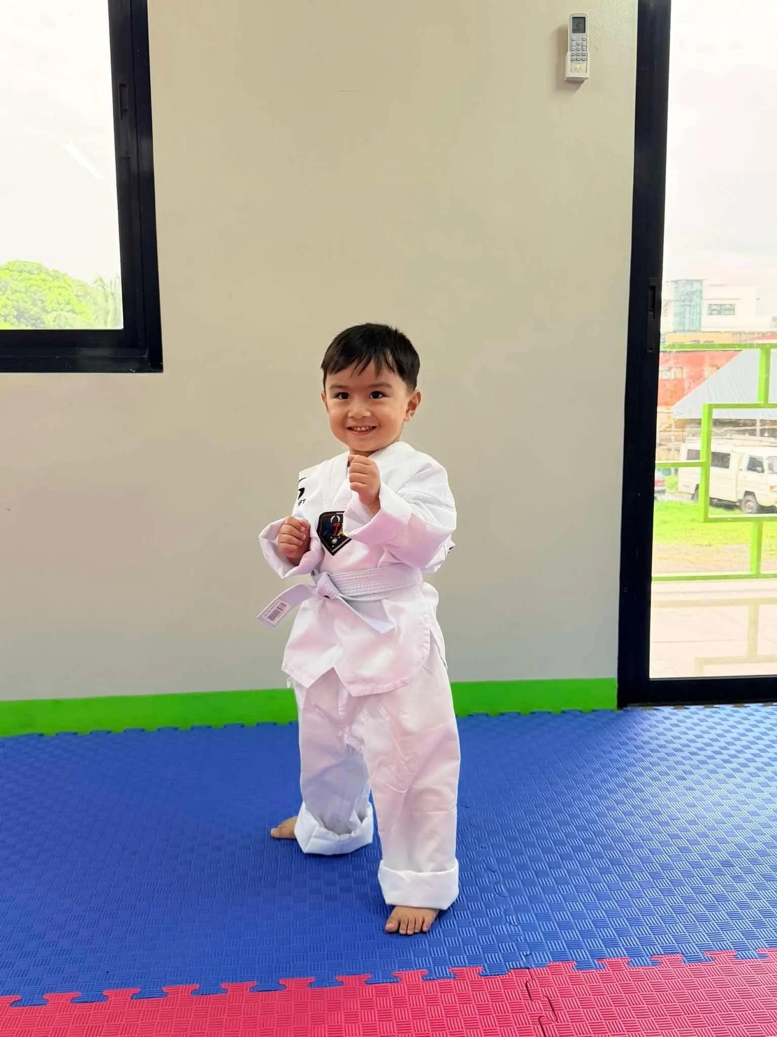 A young student practicing a taekwondo stance in the training hall