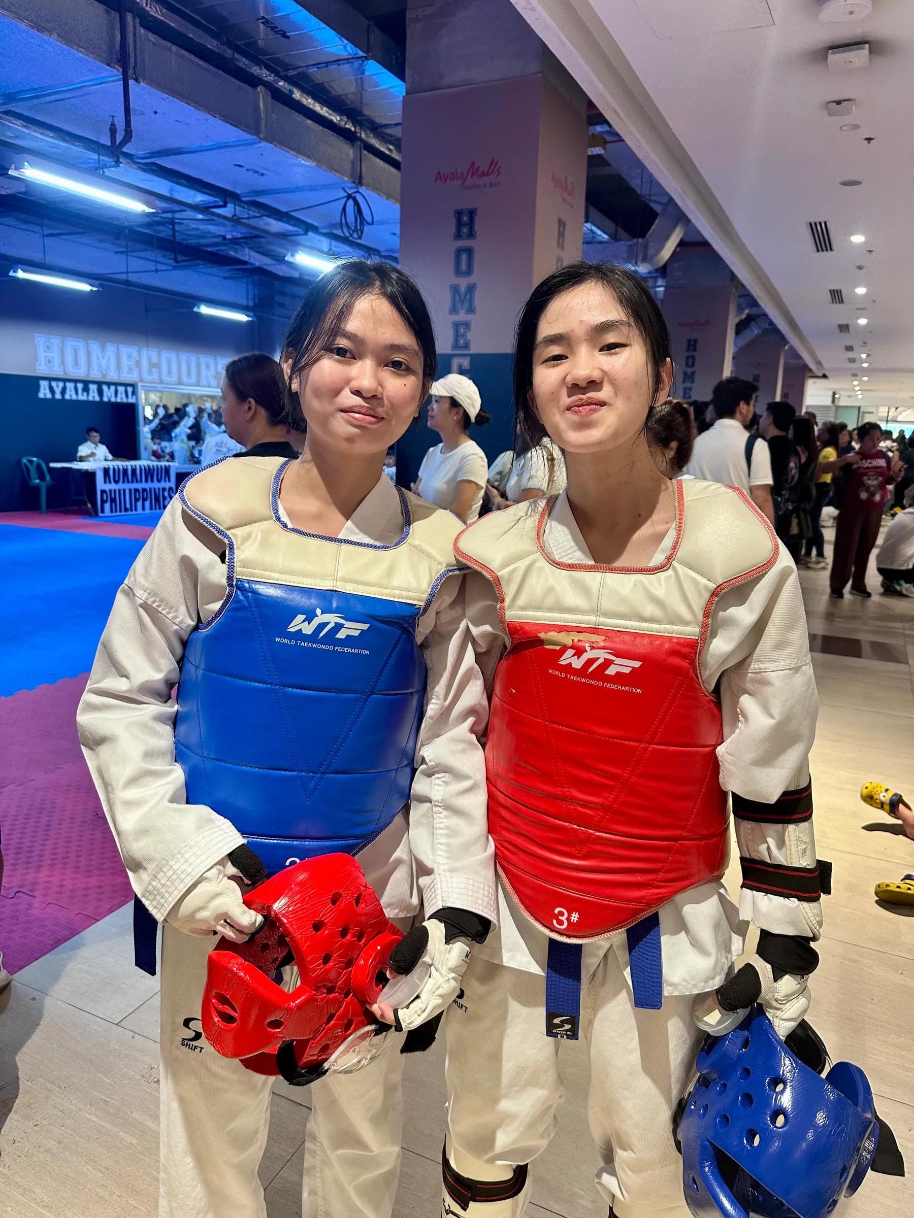 Two students in blue and red chest protectors at a tournament