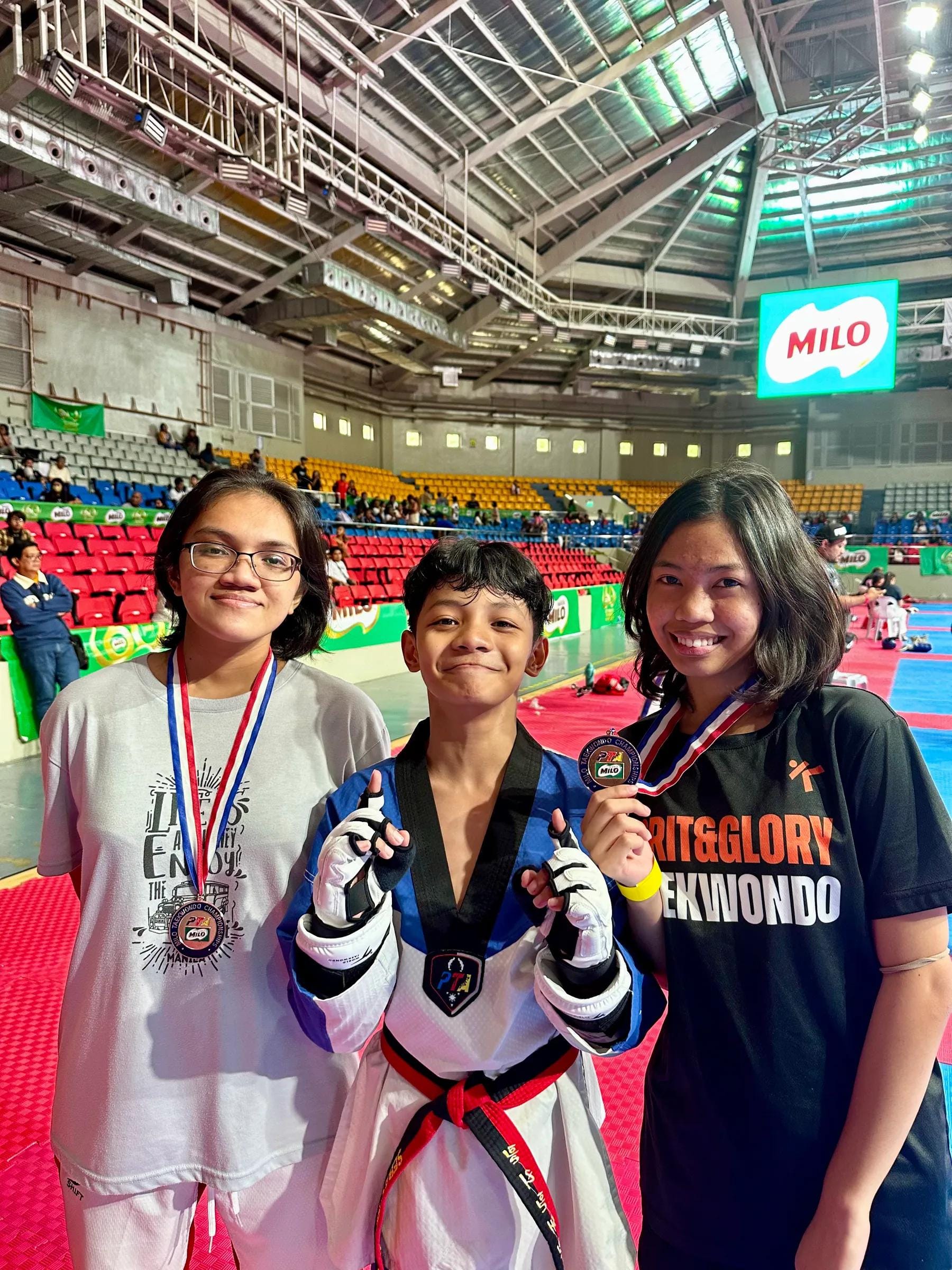 Three students with medals at a tournament arena