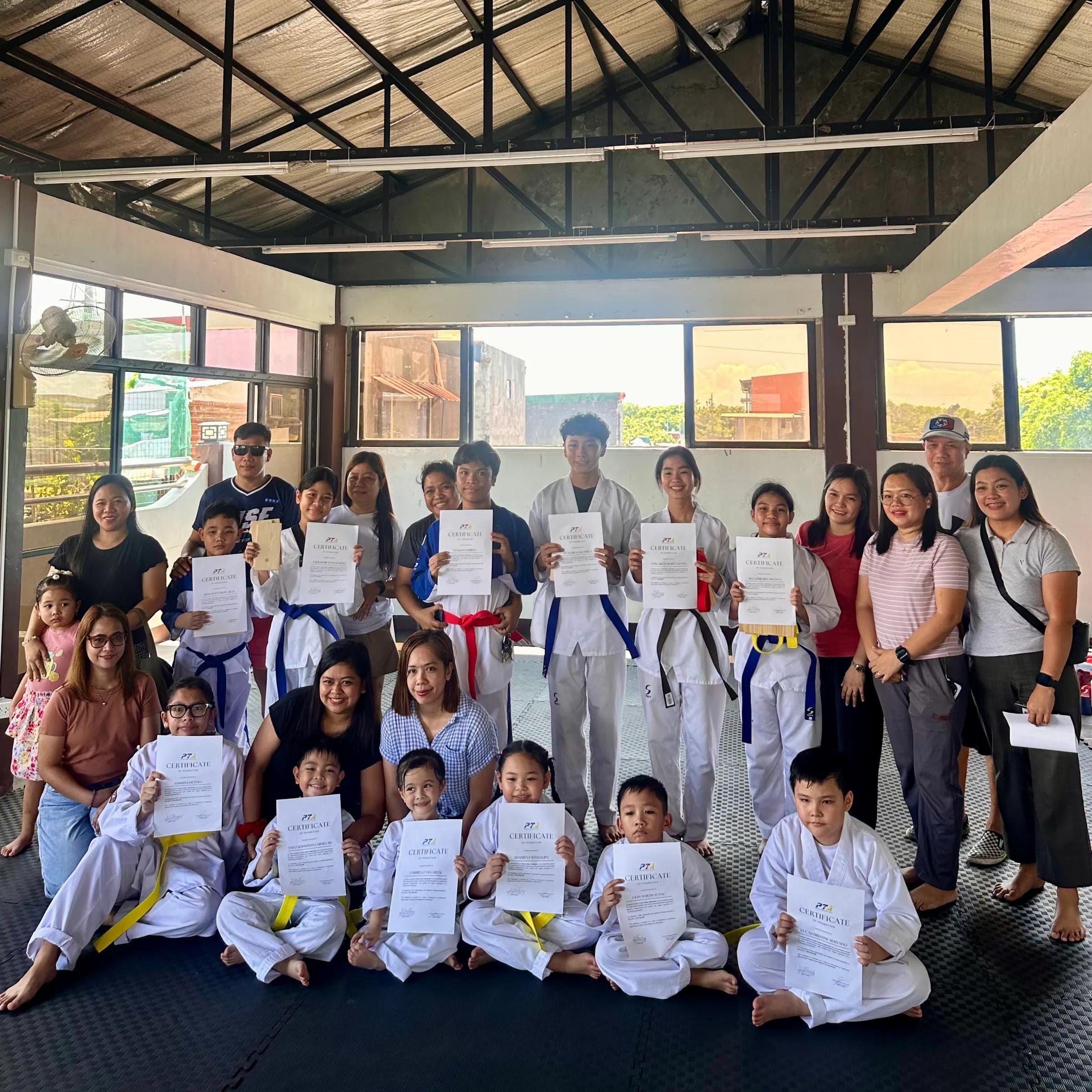 Students, families and coaches together after a grading, holding certificates