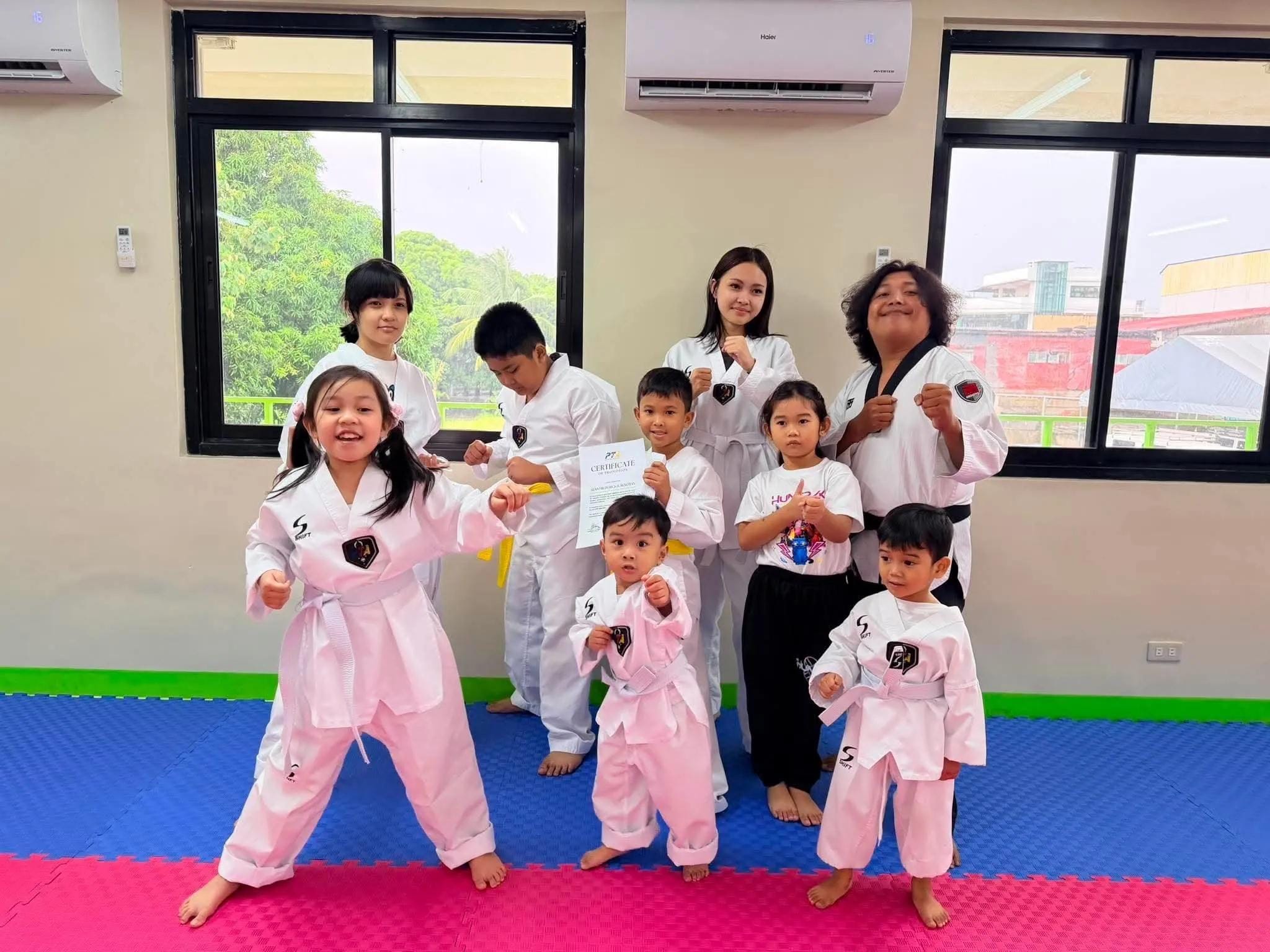 Little Tigers laughing in fighting stance, with their coaches and a student holding a grading certificate behind them