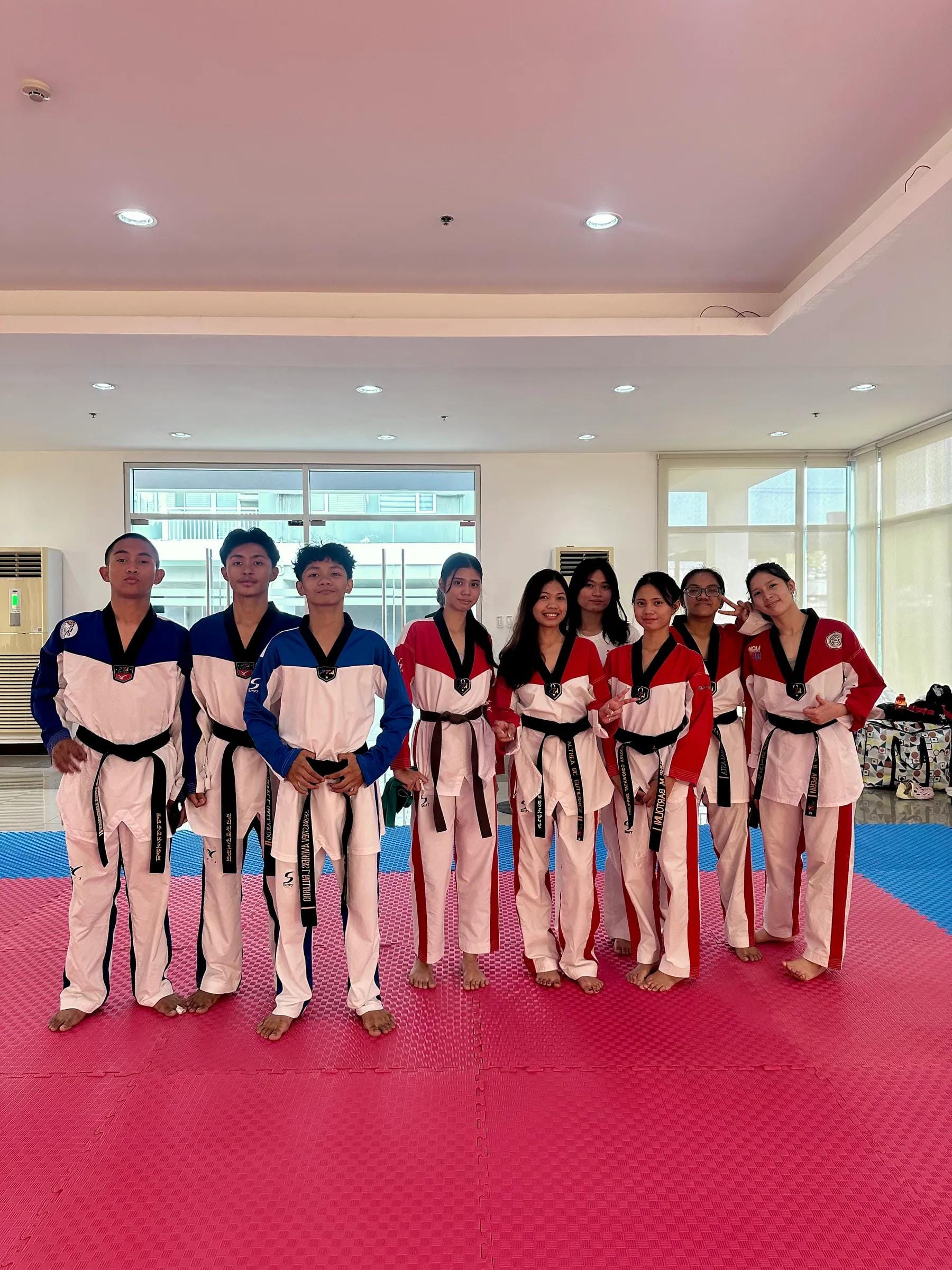 Teen and adult students in red- and blue-trimmed doboks standing together as a team