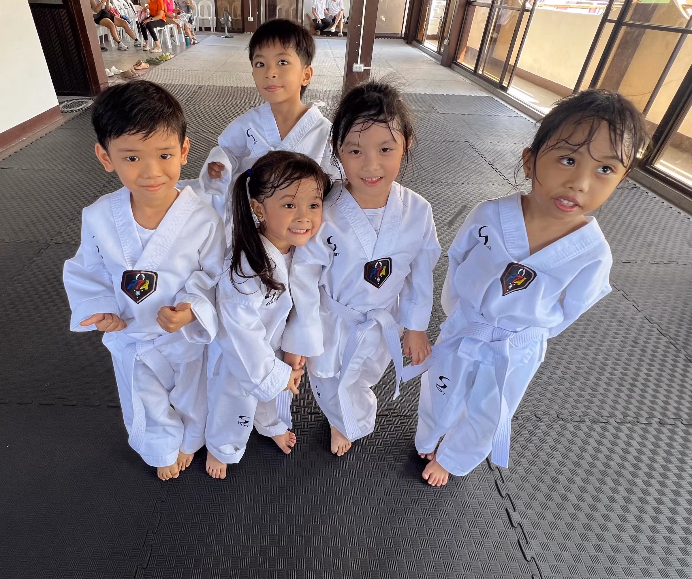 Young students in white doboks huddled together, smiling