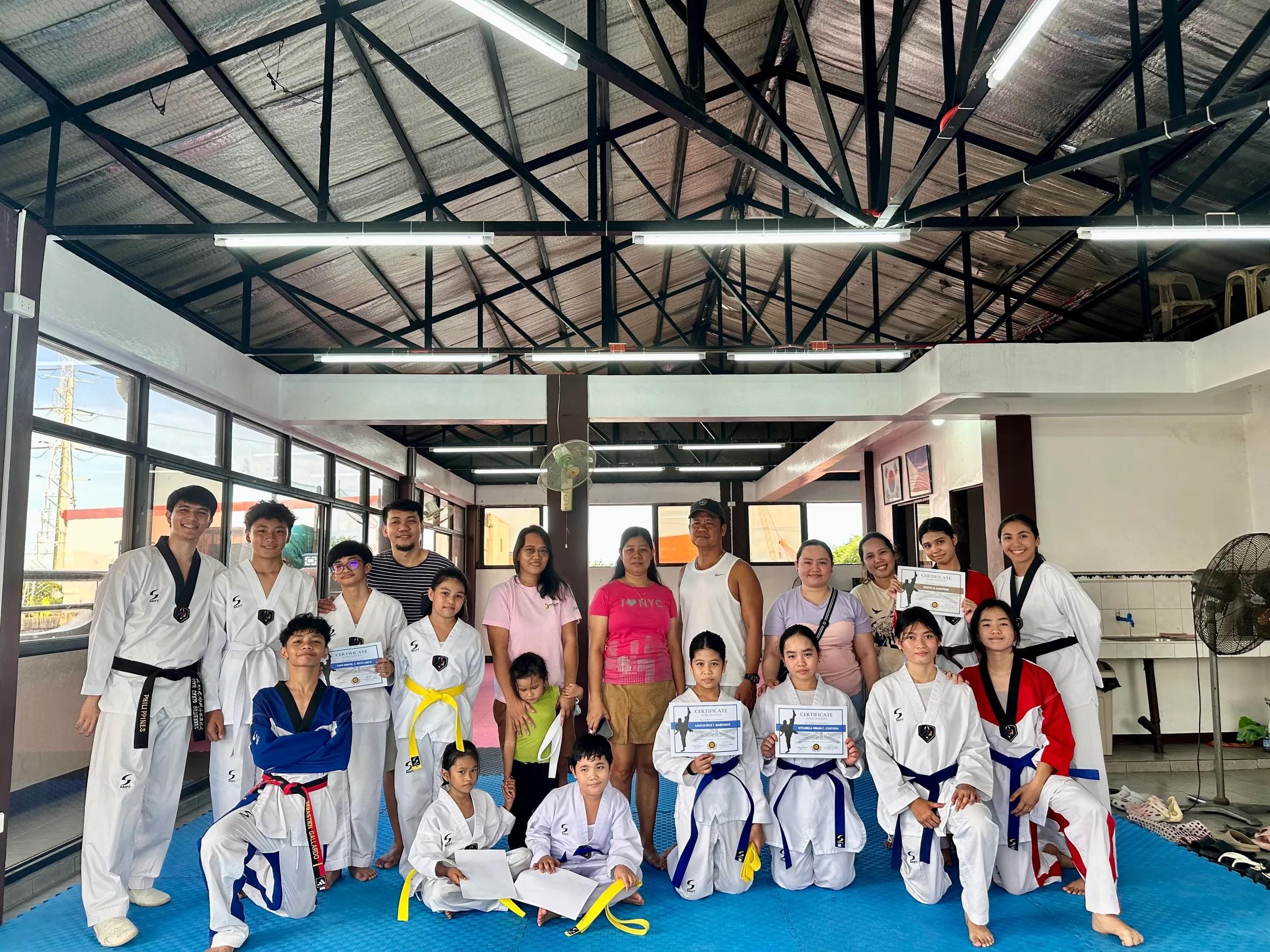 A large class with families and coaches gathered at the open-air training hall