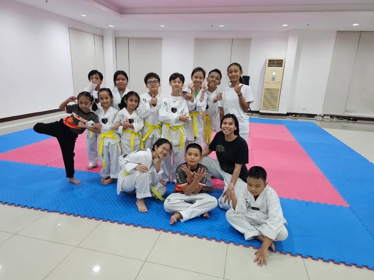 Students posing on the mat, one holding a high kick